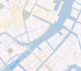 En digital karta som visar en flod som rinner genom en stad, med olika broar och gator märkta på danska. Området omfattar byggnader, parker och vattendrag som illustrerar en del av en stad med detaljplaneringslinjer.